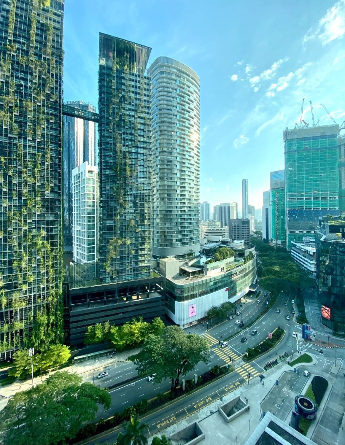 Glass towers with hanging greenery above a city street