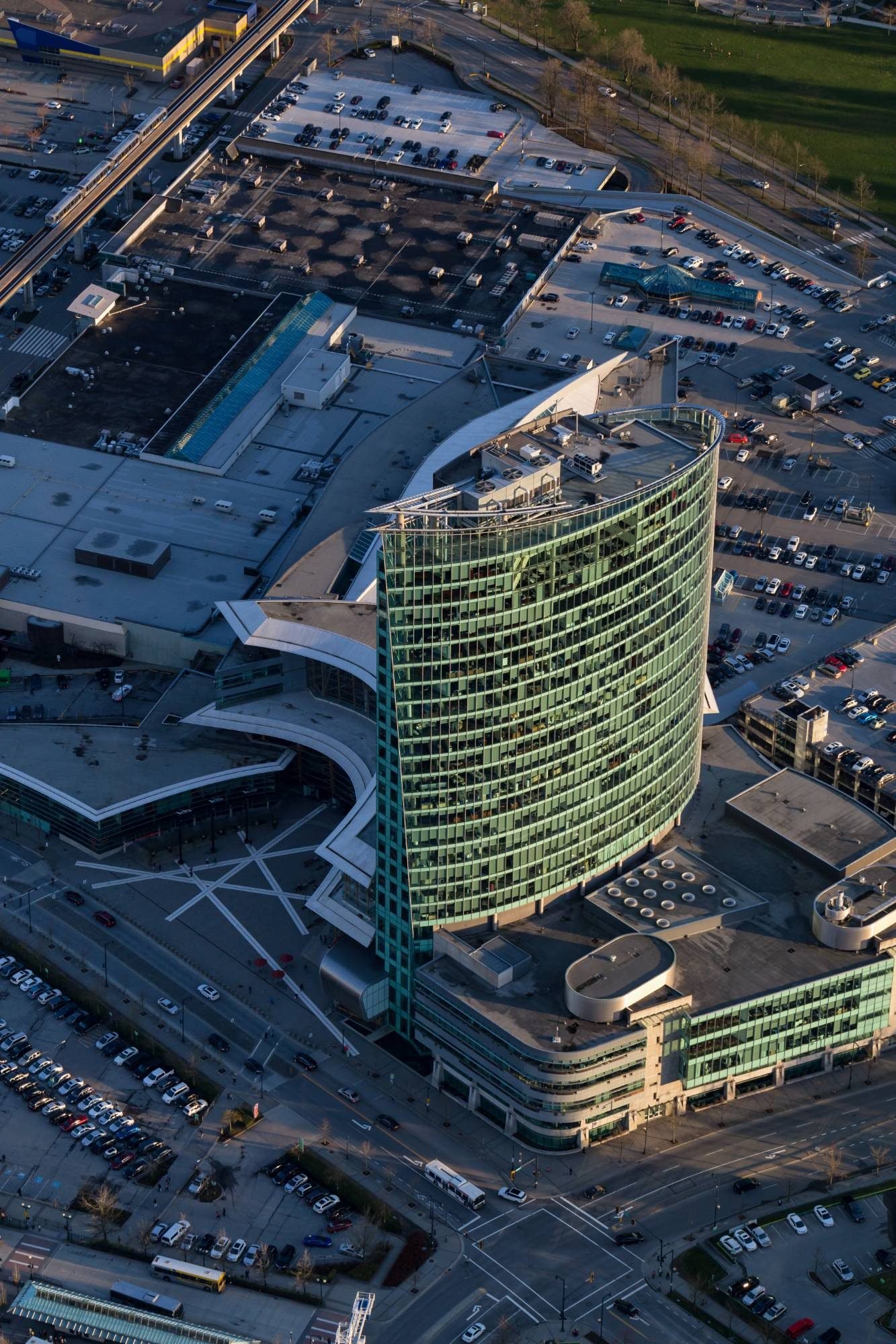 Curved green glass office tower seen from above